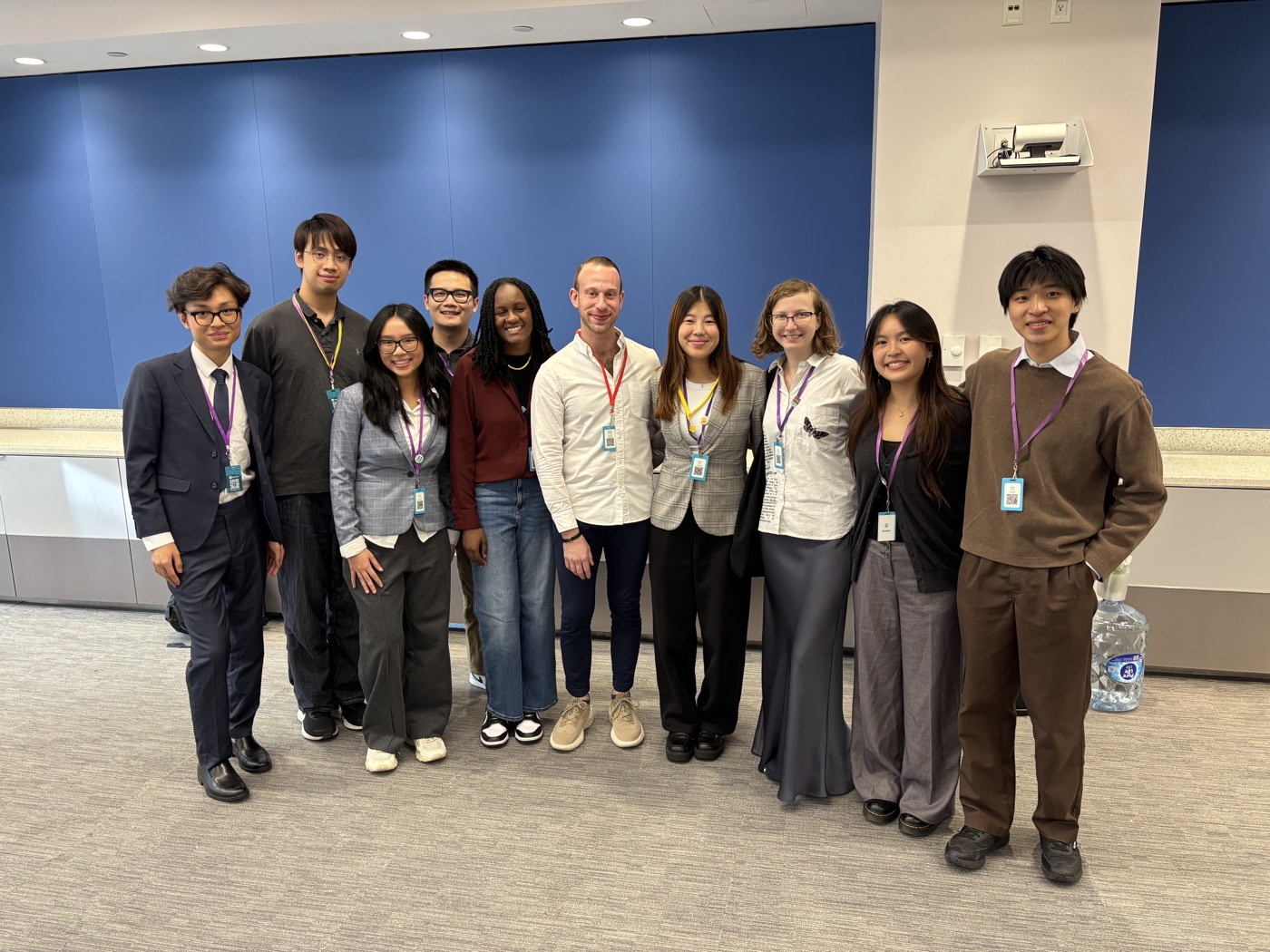 A group of students wearing conference lanyards, posed in a row against a blue wall at the O4U Digital 2025 conference.